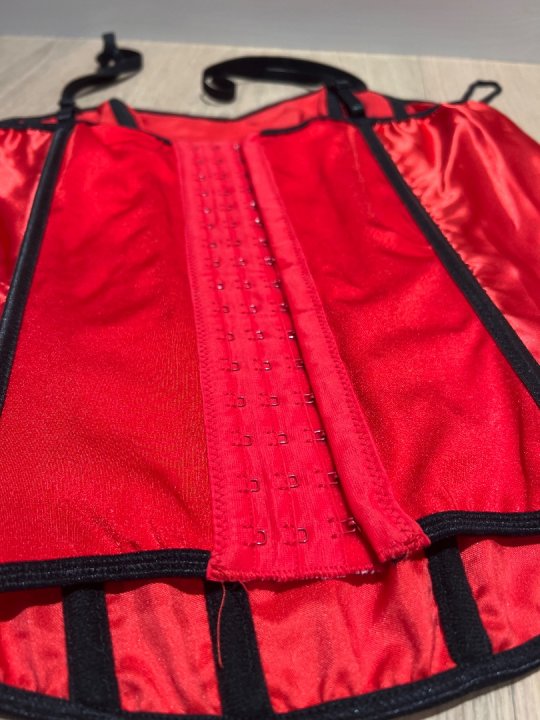 Corsage i r&oslash;d satin og h&aelig;gter p&aring; ryg. Str 40/42